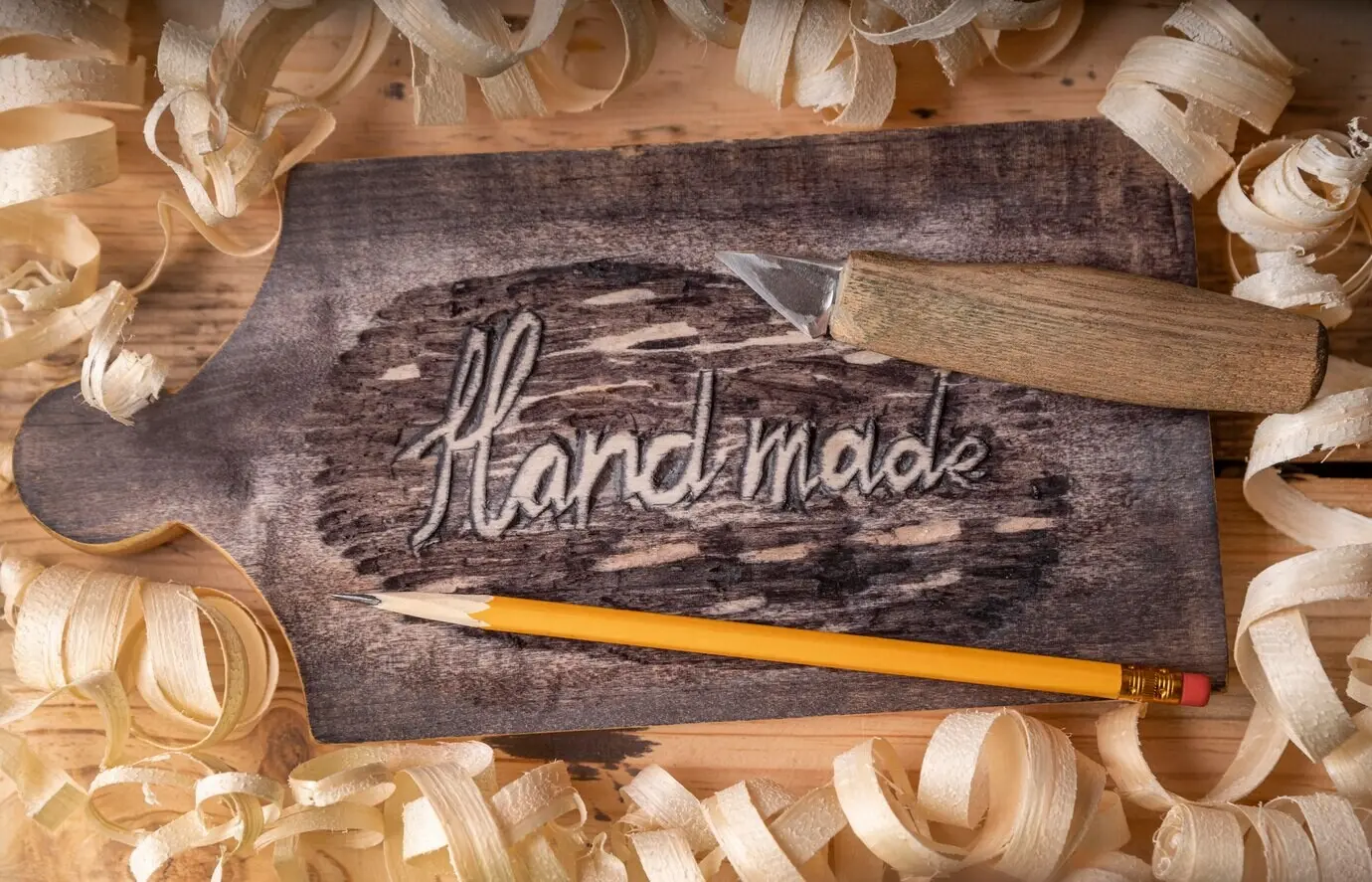 Draufsicht auf Ausrüstung für Handwerksberufe und den Schriftzug „hand made“ auf Holz.